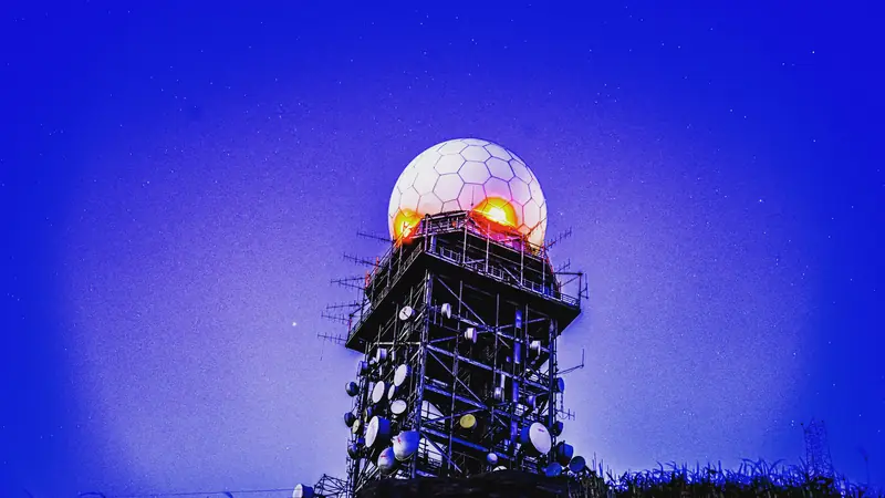 A weather radar dome glowing against a deep blue night sky.
