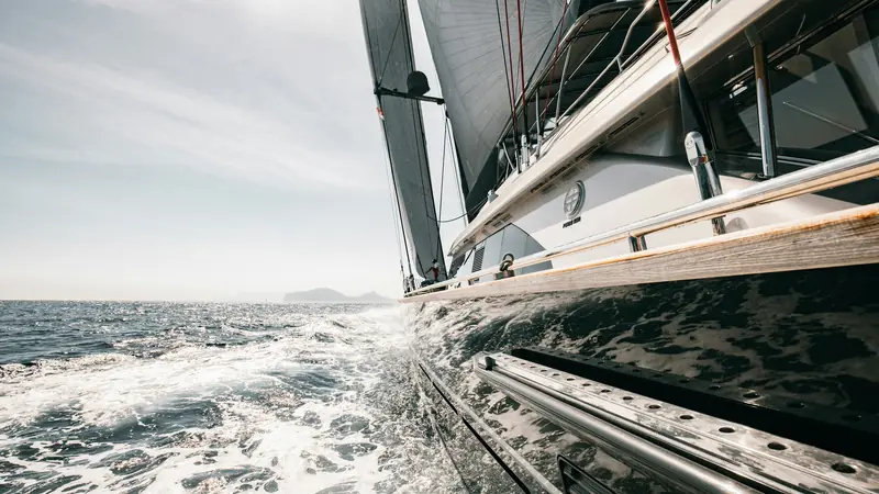 A monohull heeled hard over with its rail near the water, throwing spray.