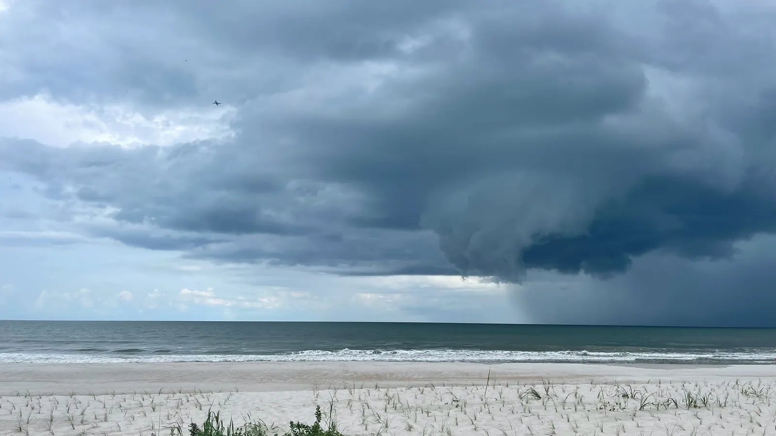 A dark shelf cloud from an advancing squall line spreading over the sea.